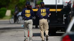FBI forensic personnel walk in front of the house where three women were held captive for a decade on May 7, 2013 in Cleveland, Ohio.