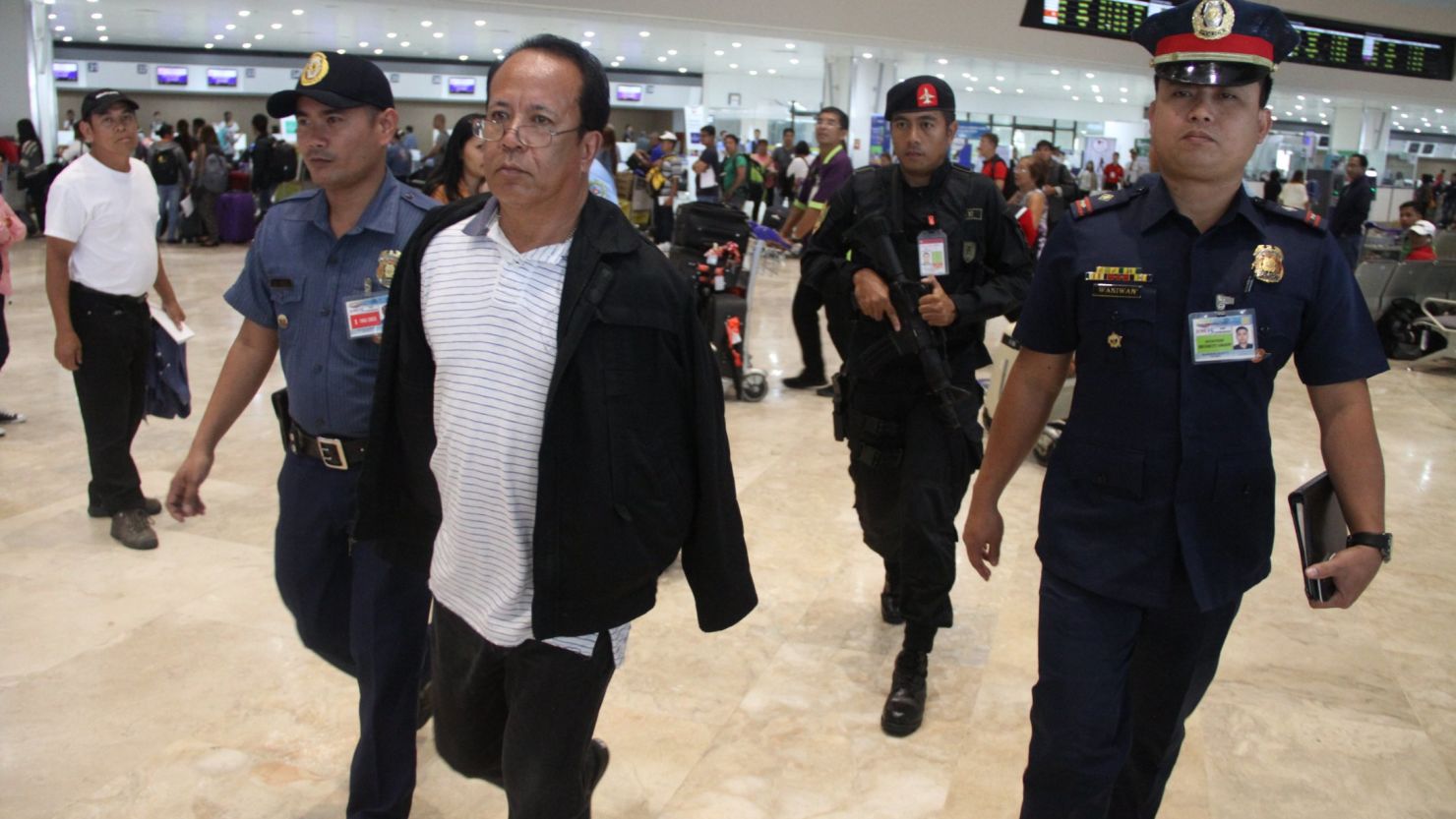 Police escort American Cipriano de Guzman at Ninoy Aquino International Airport