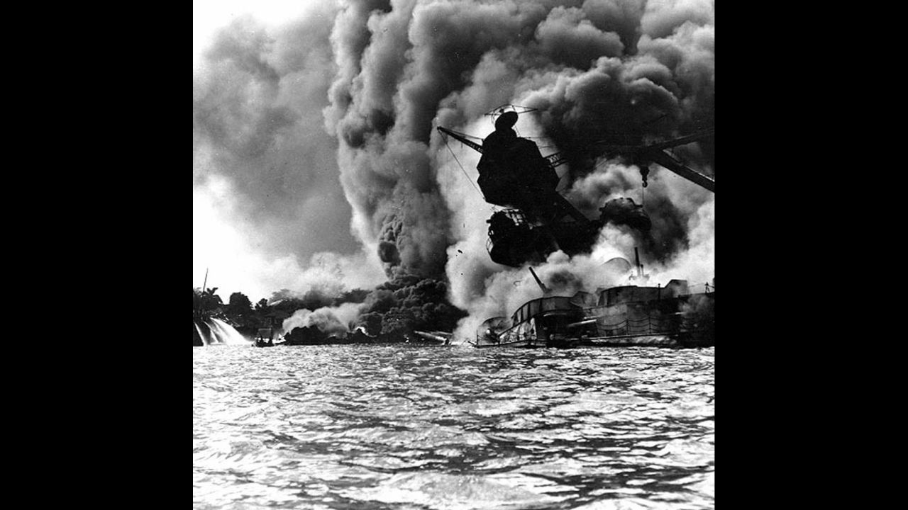 The USS Arizona burns furiously on December 7, 1941. The ship's forward magazines exploded when a Japanese bomb hit it. The remains of many of the 1,177 U.S. military personnel who died aboard the Arizona are still inside the wreck. 