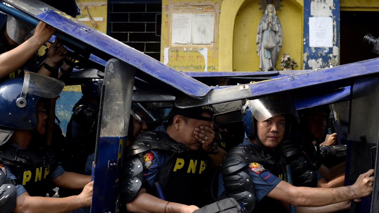 Police officers use their shields during the demolition of an informal settler community in Manila, Philippines, on Tuesday, May 26. The area is being redeveloped into a business district.