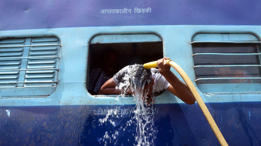 A commuter uses a train's hose to cool down at the railway station in Allahabad on Sunday, May 24.