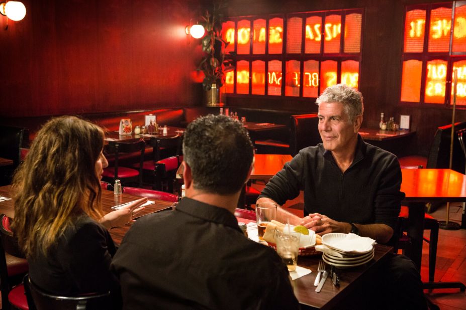 Bourdain listens over dinner as the husband-wife comedians discuss how people often think of New Jersey as an industrial wasteland because of the refineries along the turnpike.