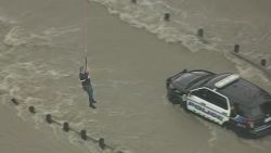 A police officer is plucked from his patrol car after a flash flood stranded him.