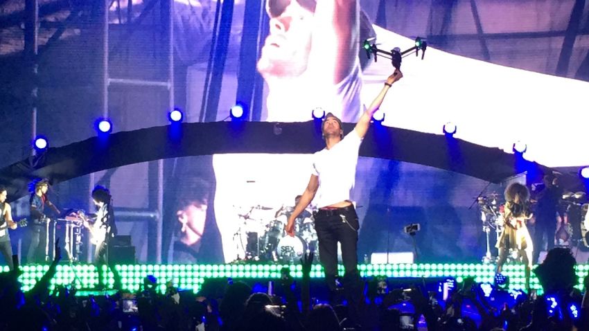 In this photo provided by Francis Ramsden, Enrique Iglesias grabs a drone onstage during a concert in Tijuana, Mexico on Saturday, May 30, 2015. A representative for the singer says in a statement to The Associated Press that Iglesias was "semi-treated" offstage after his fingers were sliced when he grabbed the drone. During live shows, Iglesias sometimes grabs a drone to show the audience a "point of view" angle. (Francis Ramsden via AP)