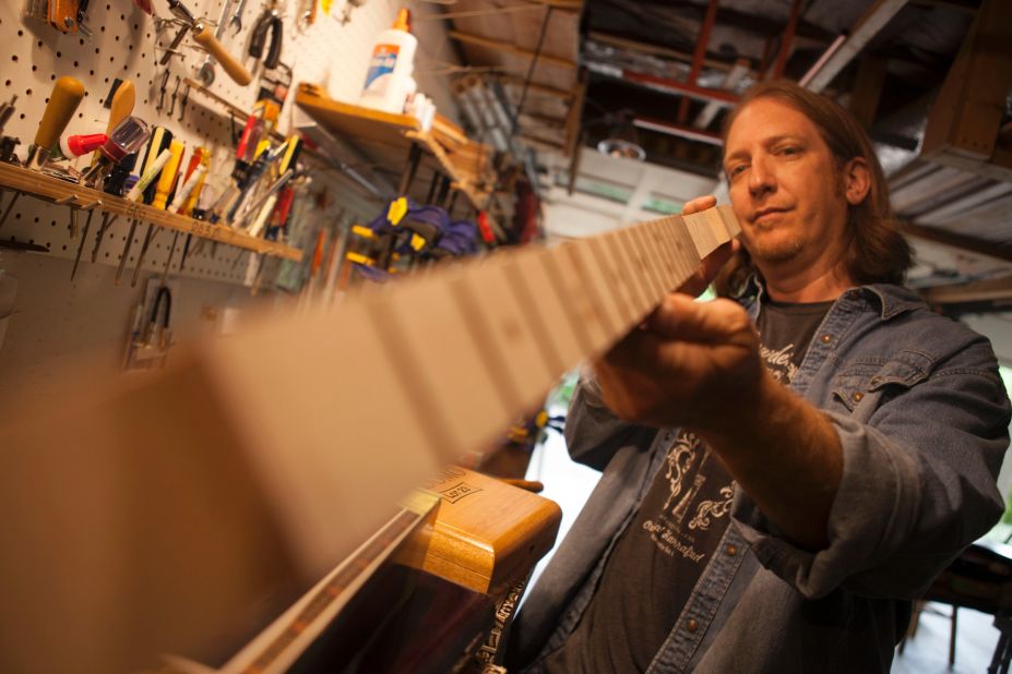 After fretting the cigar box guitar neck, Snowden holds it up to make sure the frets are even and the neck is straight. 