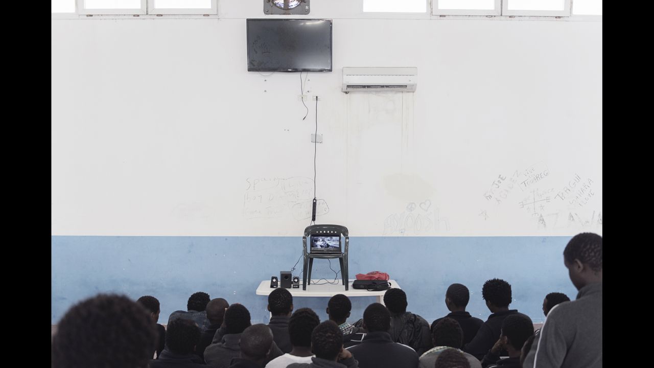 Migrants at the center watch a movie on a small laptop screen. The television above didn't work.