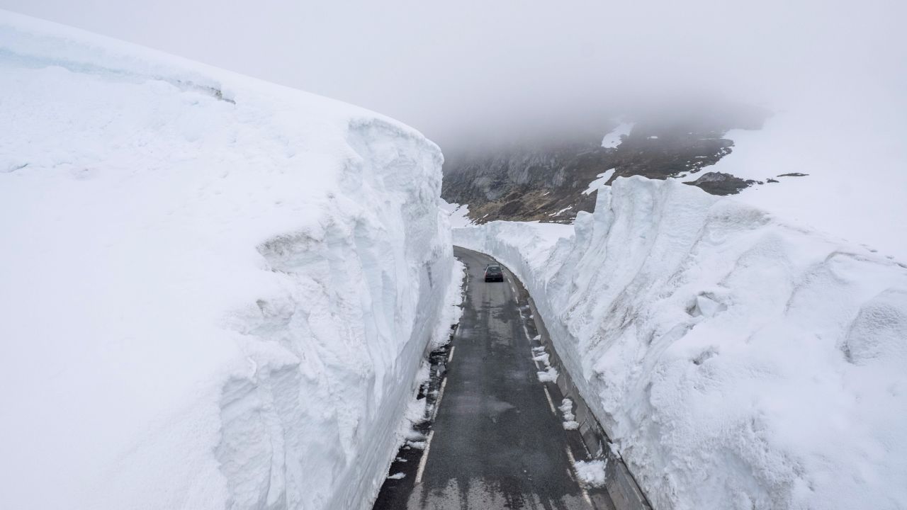 A car drives past walls of snow on a mountain road in Norway on Saturday, May 30.
