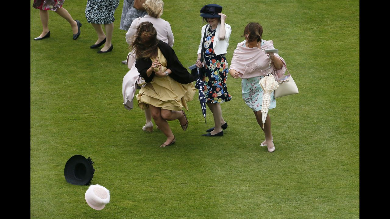 Women run after their hats Tuesday, June 2, during a windy garden party at Buckingham Palace in London.