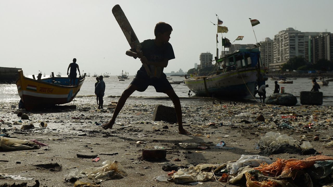 A boy plays cricket on a garbage-covered beach in Mumbai, India, on Wednesday, June 3.