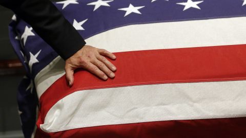 Biden rests his hand on the flag-draped casket. 