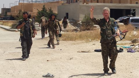 Enright, right, wears the military uniform of Kurdish fighters and flashes a victory sign last month in Syria.
