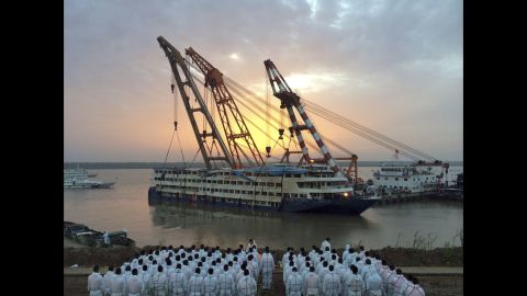 Paramilitary police in white overalls wait to recover bodies from the ship after it was righted and lifted by cranes from the Yangtze River in Jianli, China, on Friday, June 5.