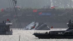 Marine boats patrol as a capsized ship is righted by cranes on the Yangtze River in Jianli county of southern China's Hubei province, as seen from across the river from Huarong county of southern China's Hunan province, Friday, June 5, 2015. The boat had been righted and teams would still try to lift the vessel even though the water inside it was weighing it down. Transport Ministry spokesman Xu Chengguang said earlier that the operation would involve divers putting steel bars underneath the ship, which would then be lifted by two 500-ton cranes. (AP Photo/Andy Wong)