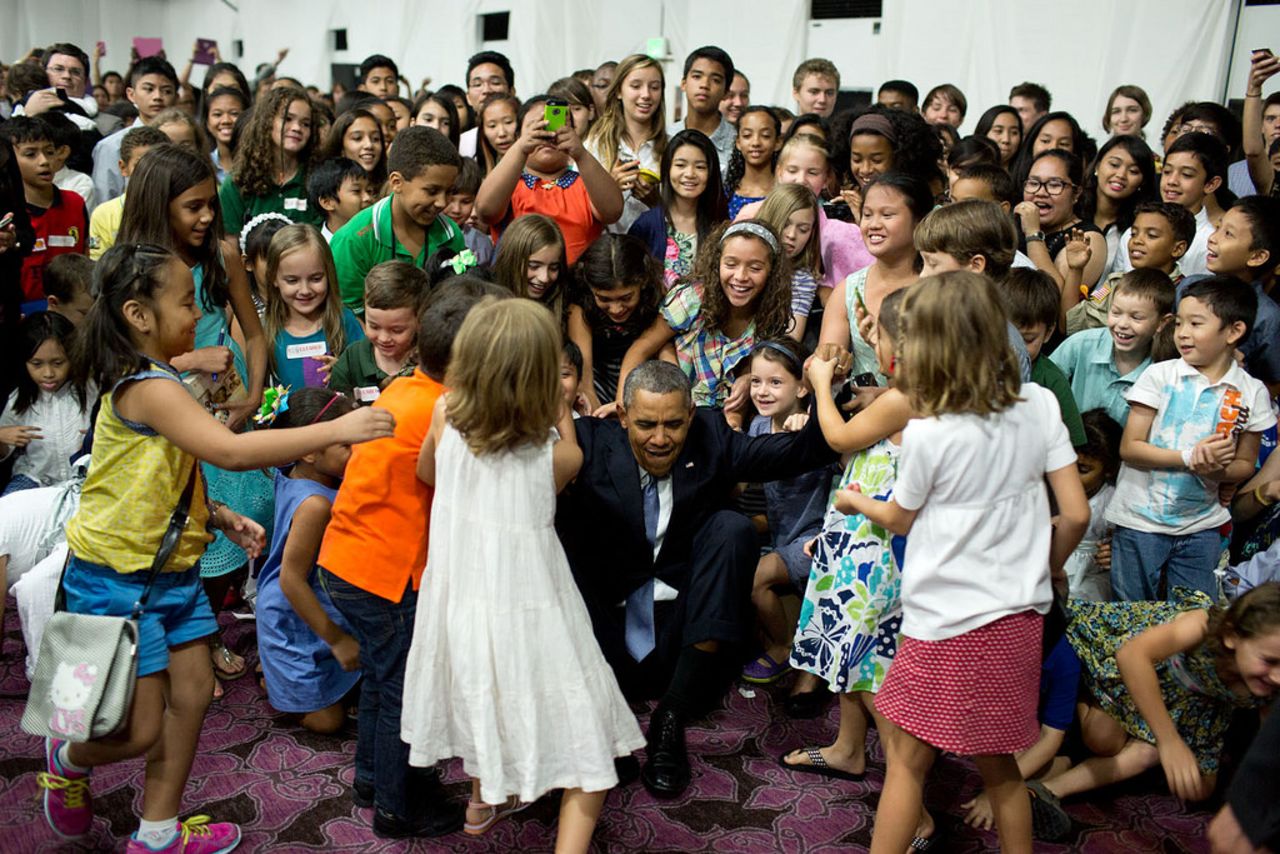 Obama beckons for help to get up after posing for a photograph with children at the U.S. Embassy in Manila, Philippines.