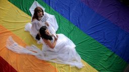 Supporters of LGBT rights dressed in wedding gowns sit on a rainbow banner at the University of the Philippines (UP) campus in Manila on June 27, 2013 as they celebrate Pride Month.
