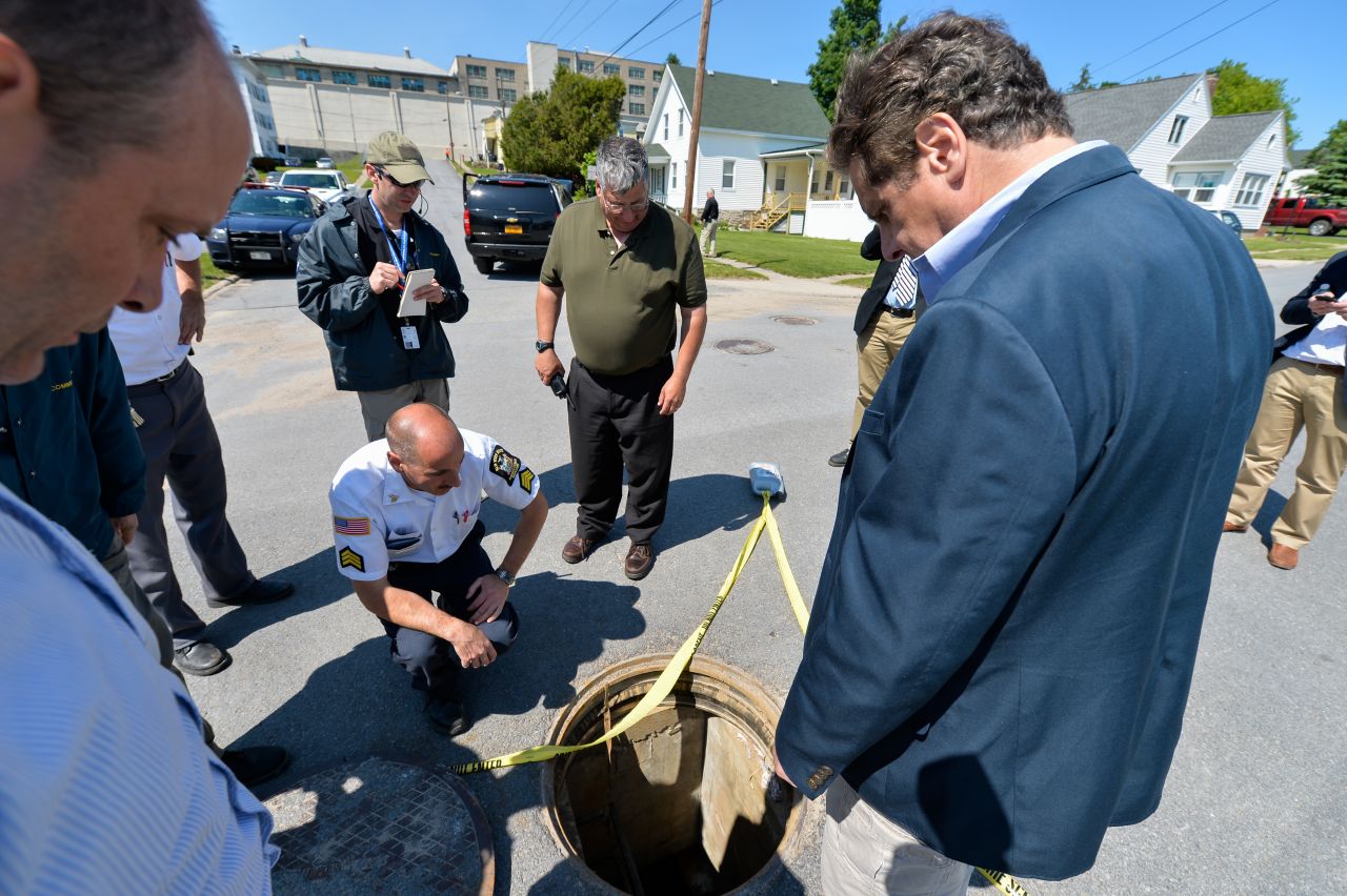 Officials look at the manhole through which the inmates crawled to freedom.