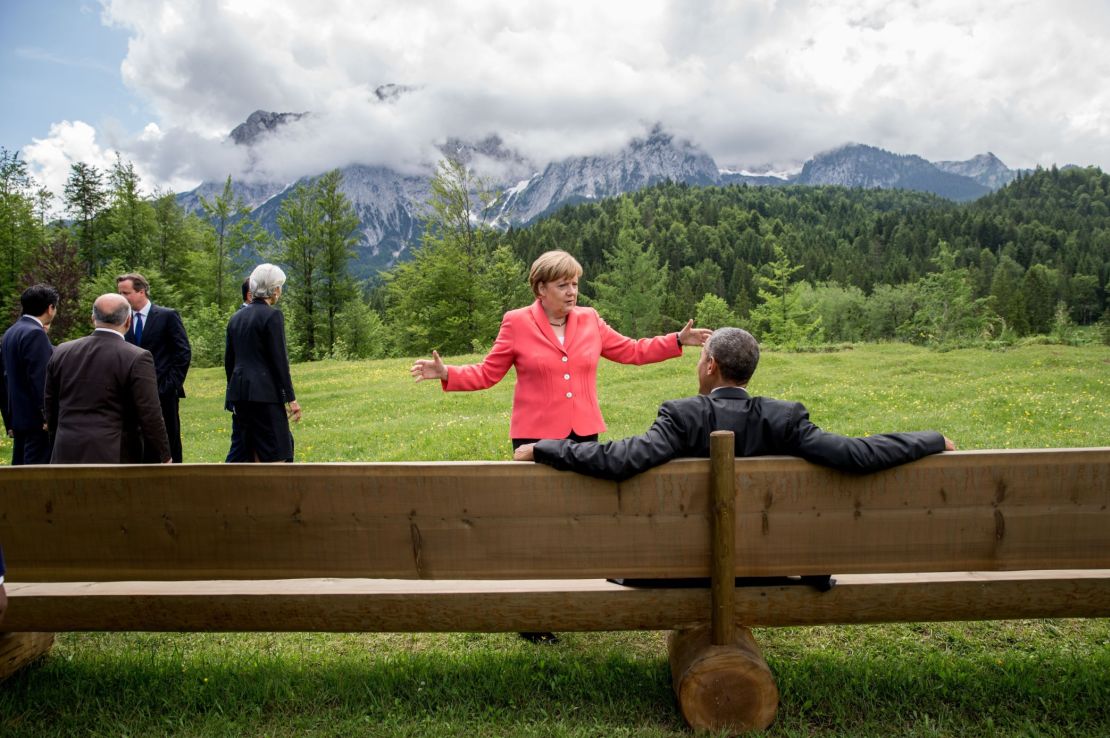 Germany's Chancellor Angela Merkel (C) gestures while chatting with US President Barack Obama sitting on a bench outside the Elmau Castle after a so-called outreach meeting at a G7 summit near Garmisch-Partenkirchen, southern Germany, on June 8, 2015.