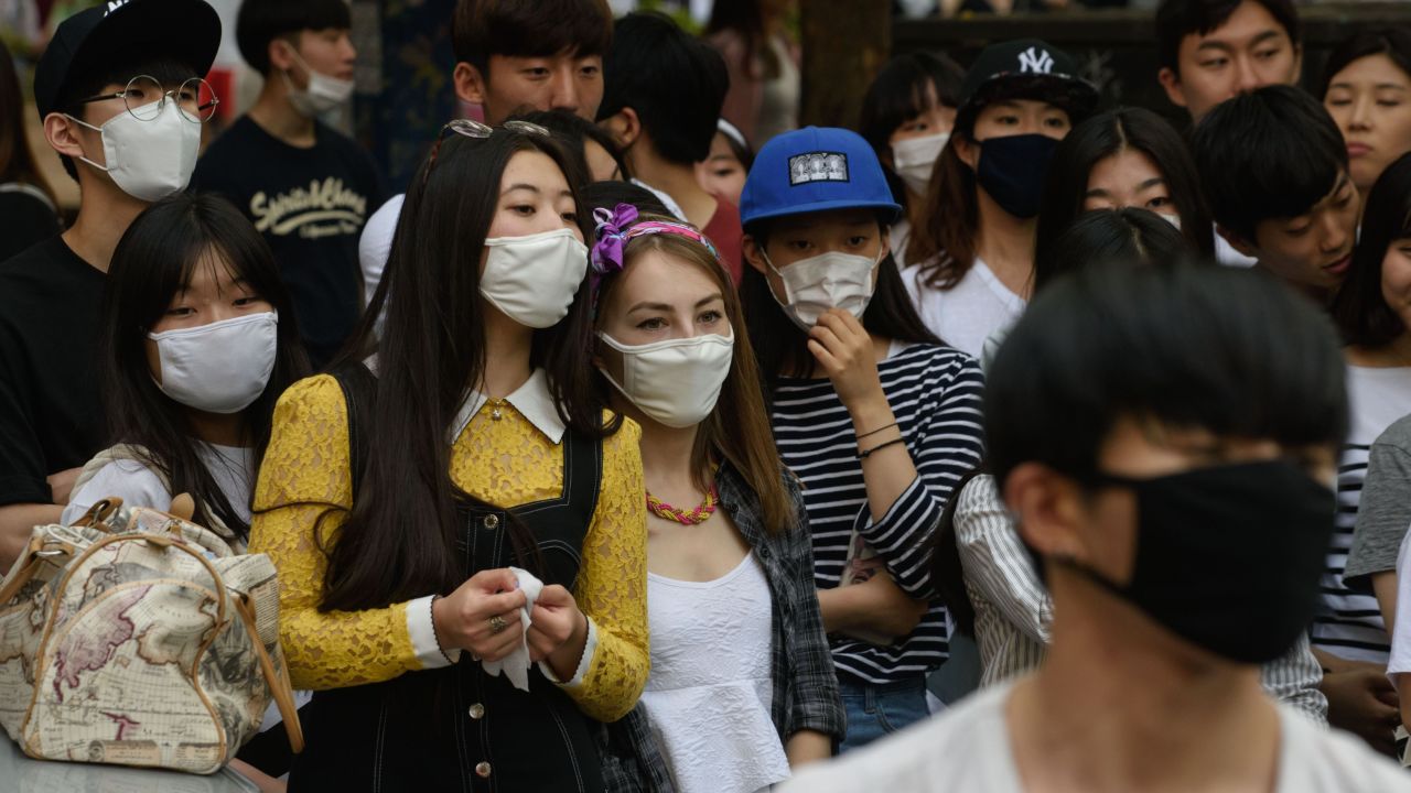 People wearing face masks watch a K-Pop performance on a street in the popular student area of Hongdae in Seoul on June 7, 2015. South Korea reported its fifth death from MERS as the government on June 7 vowed 'all-out' measures to curb the outbreak that was threatening to spread nationwide, including tracking mobile phones of those in quarantine. AFP PHOTO / Ed Jones (Photo credit should read ED JONES/AFP/Getty Images)