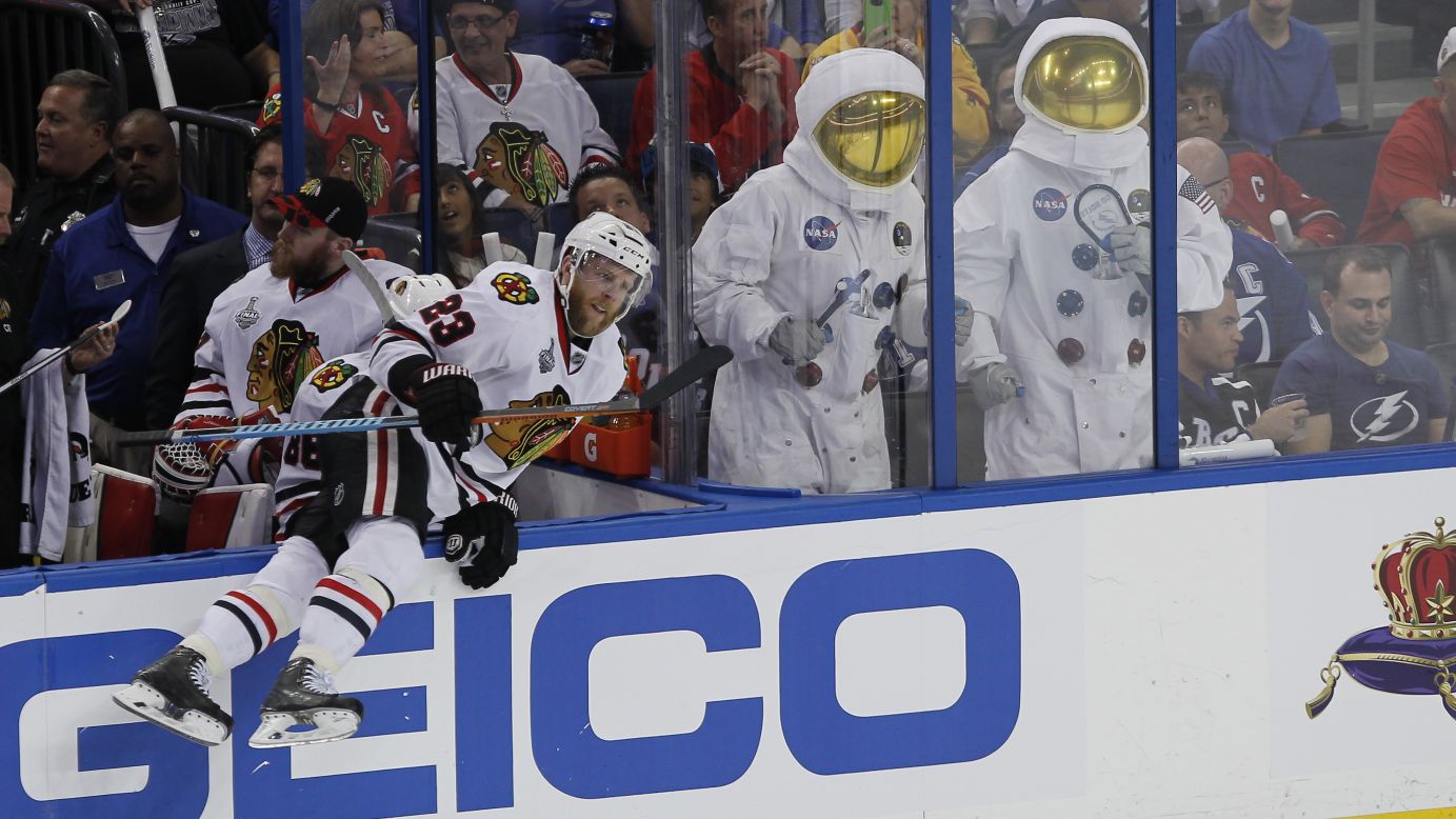 Chicago's Kris Versteeg jumps onto the ice Saturday, June 6, near two Tampa Bay Lightning fans dressed as astronauts. Chicago and Tampa Bay split the first two games of the Stanley Cup Final. 