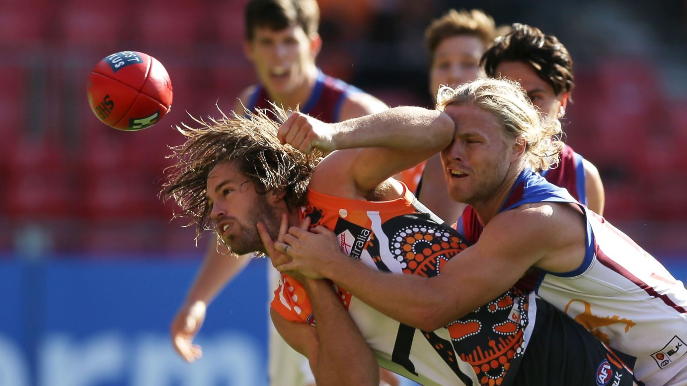 Callan Ward of the Greater Western Sydney Giants is hit by one of the Brisbane Lions while passing the ball Sunday, June 7, during an Australian Football League match in Sydney.