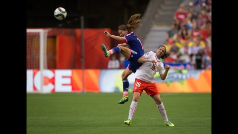 Japan's Rumi Utsugi kicks the ball out of the air as she jumps above Switzerland's Fabienne Humm.