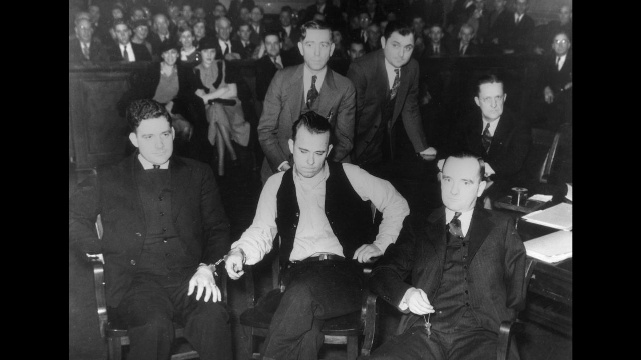 American criminal John Dillinger, center, sits in court in 1934 after being accused of killing a police officer. Later that year, he escaped an Indiana jail wielding a wooden gun he whittled. After imprisoning guards, he drove away in the sheriff's car. A few months later, he was shot dead outside of a theater in Chicago.
