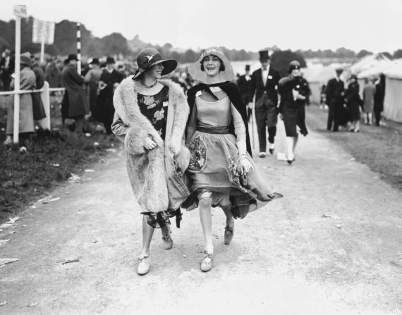 Two spectators wear floral dresses with wide-brimmed straw hats at Royal Ascot in the summer of 1928. Luxury clothing labels with connections to the worlds of horse racing and equestrian sport are reporting a resurgence of interest in classic styles.