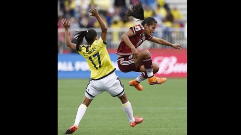 Mayor jumps next to Colombian midfielder Carolina Arias. 