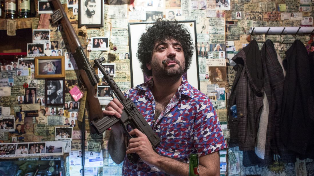 A man poses with a gun at Abu Elie, a bar in Beirut, Lebanon known for decor featuring military paraphernalia and communist iconography.