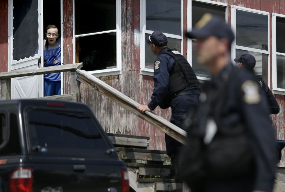 Law enforcement officers question a woman who lives near the Dannemora prison on Wednesday, June 10.