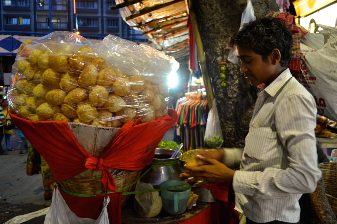 A puchka vendor makes a small hole in the fried dough ball, which will then be stuffed with filling and dunked into a tamarind and green mango sauce. 