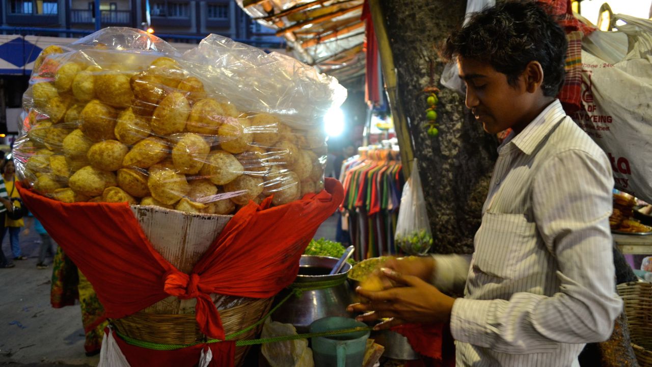 A puchka vendor makes a small hole in the fried dough ball, which will then be stuffed with filling and dunked into a tamarind and green mango sauce. 