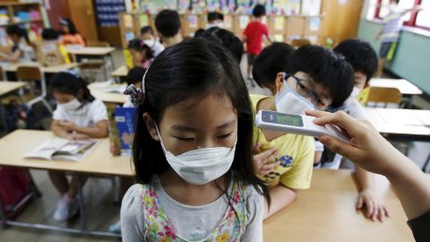 An elementary school student wearing a mask to prevent contracting MERS, receives a temperature check at an elementary school in Seoul, South Korea, on Tuesday, June 9.