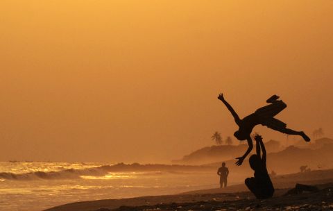Ghana's capital comes in at number seven, with 528,897 visitors predicted this year. Boys practice somersaults on Accra beach. 