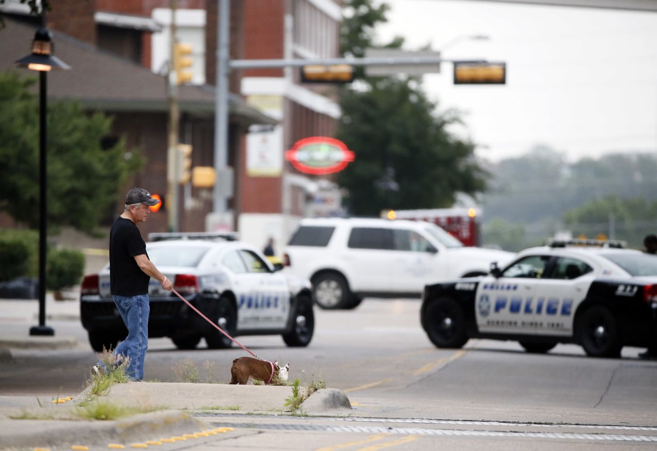 A resident walks his dog past police blocking the road near Dallas Police Department headquarters.