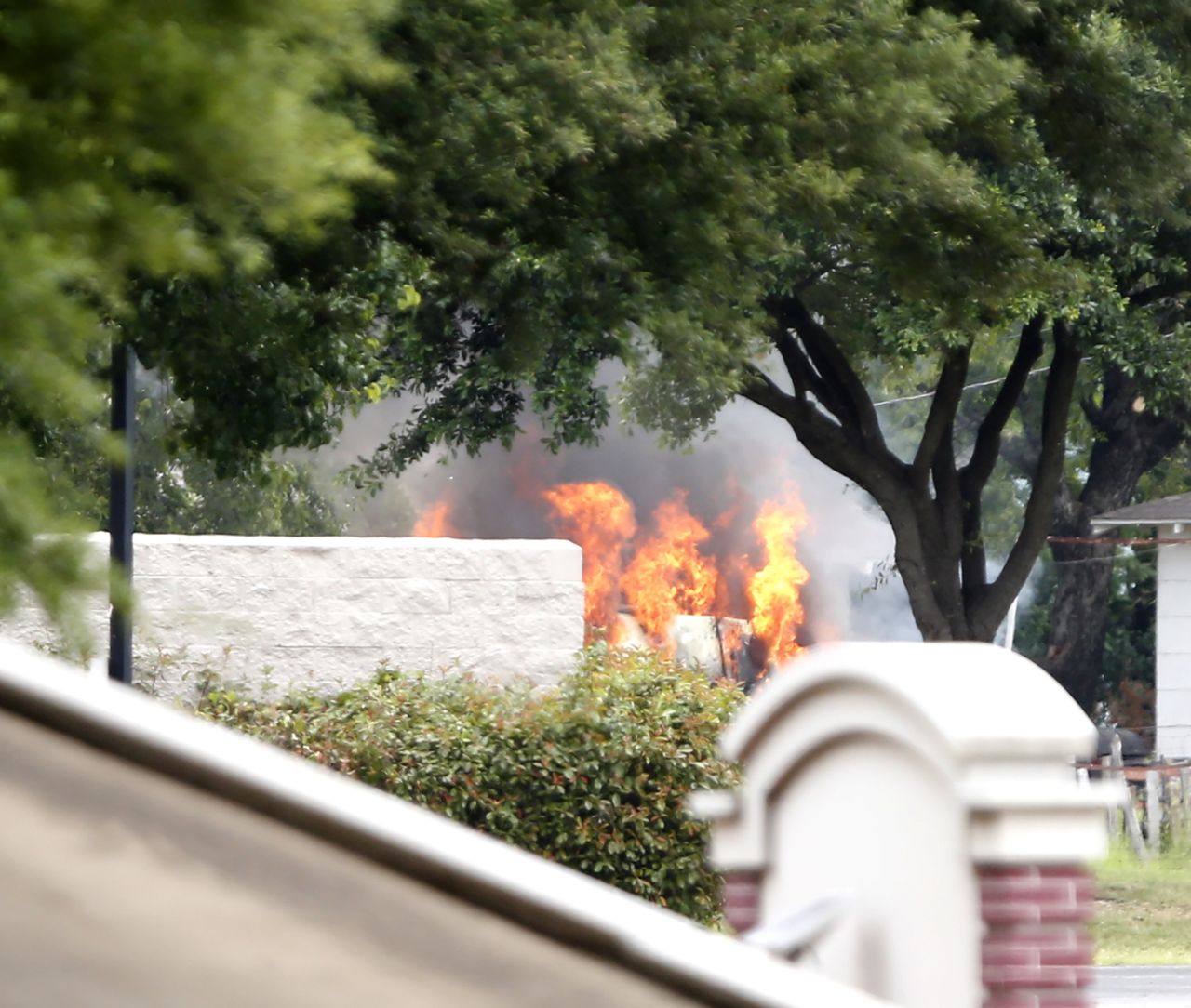 The van used by a lone shooter to attack and then flee Dallas Police Headquarters catches fire outside a fast-food restaurant on June 13, in Hutchins, Texas. Authorities used controlled charges to discharge pipe bombs in the van after the shooter reportedly unleashed multiple rounds and planted explosive devices around the station before leading police on a chase that ended in a standoff in the parking lot of the restaurant.