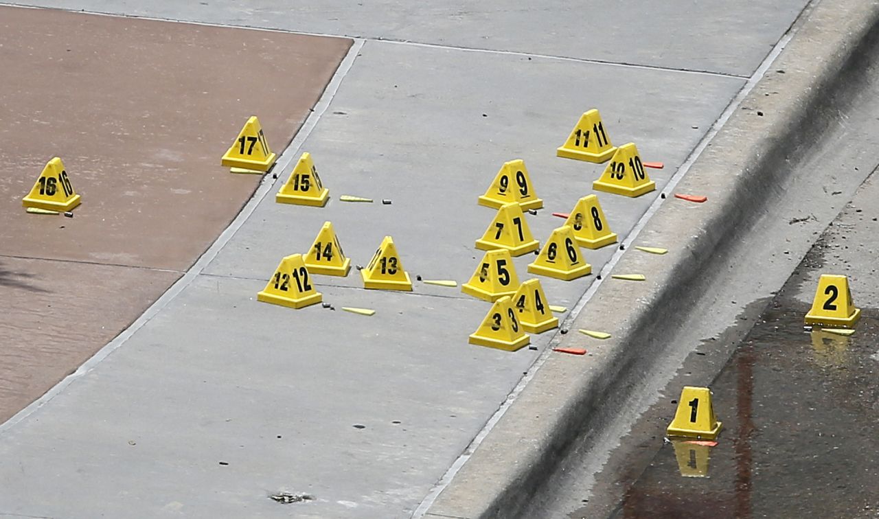 Evidence markers sit by bullet casings on a sidewalk near the police headquarters. 