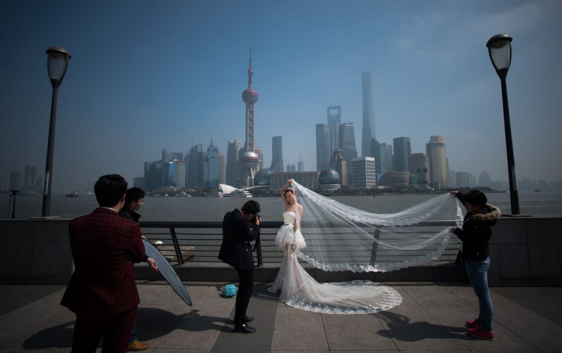 A woman poses for a wedding picture at the Bund in front of the financial district of Pudong in Shanghai on a sunny day on March 19, 2015. 