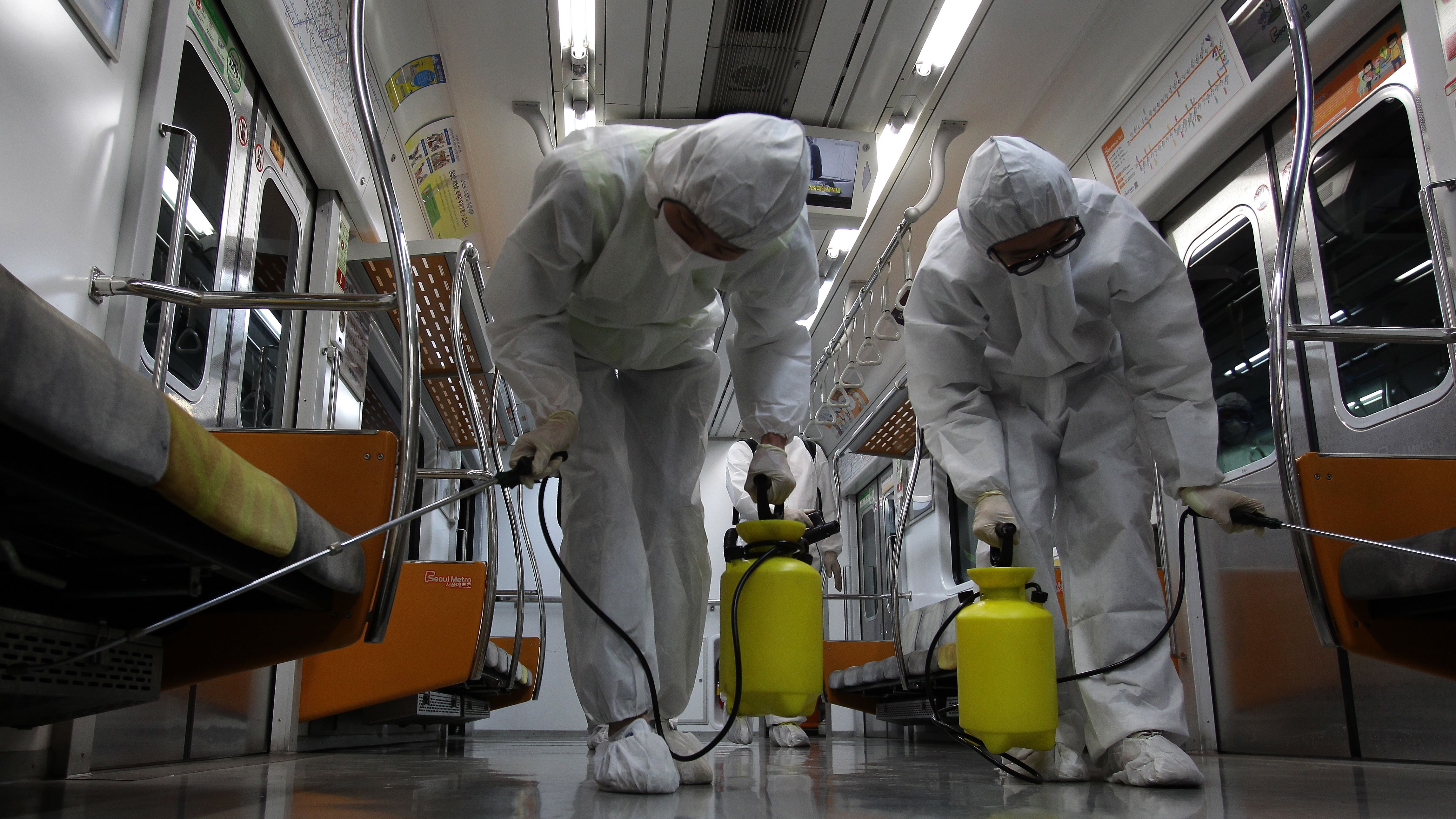 Workers wearing protective gear spray antiseptic solution in the subway amid rising public concerns over the spread of the MERS virus, on June 9, 2015, in Goyang, South Korea.