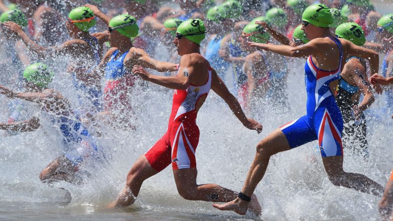 Competitors charge into the water Saturday, June 13, to start the women's triathlon at the European Games.