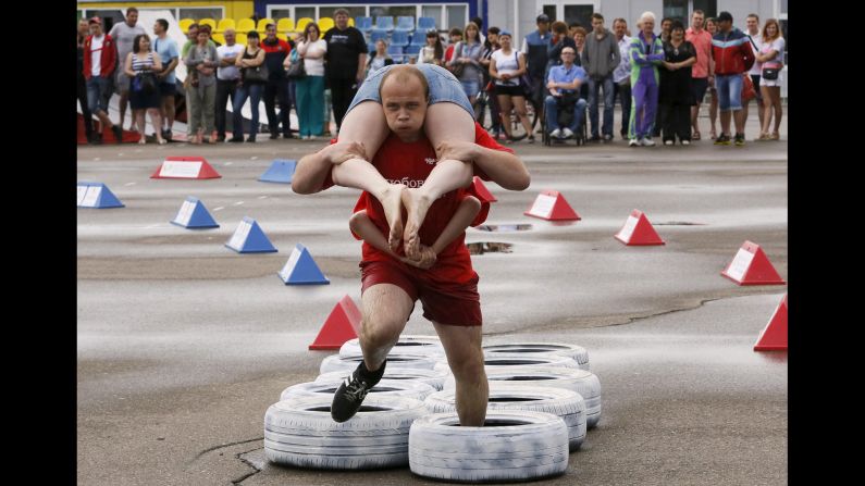 A man carries his wife through an obstacle Friday, June 12, while competing in the Wife Carrying Championship in Krasnoyarsk, Russia. 