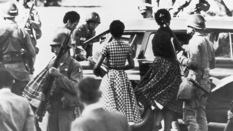 Black students are provided with a military escort when entering and leaving Little Rock Central High School, Arkansas, following the school's desegregation in 1957. 
