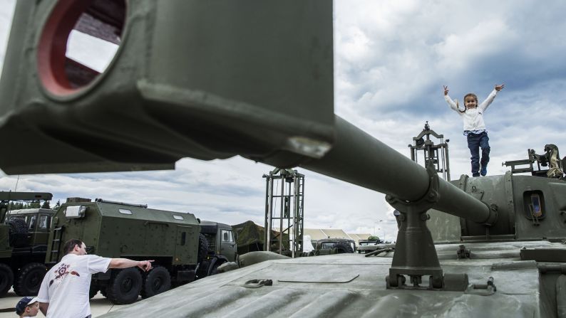  A girl plays on top of field artillery. 