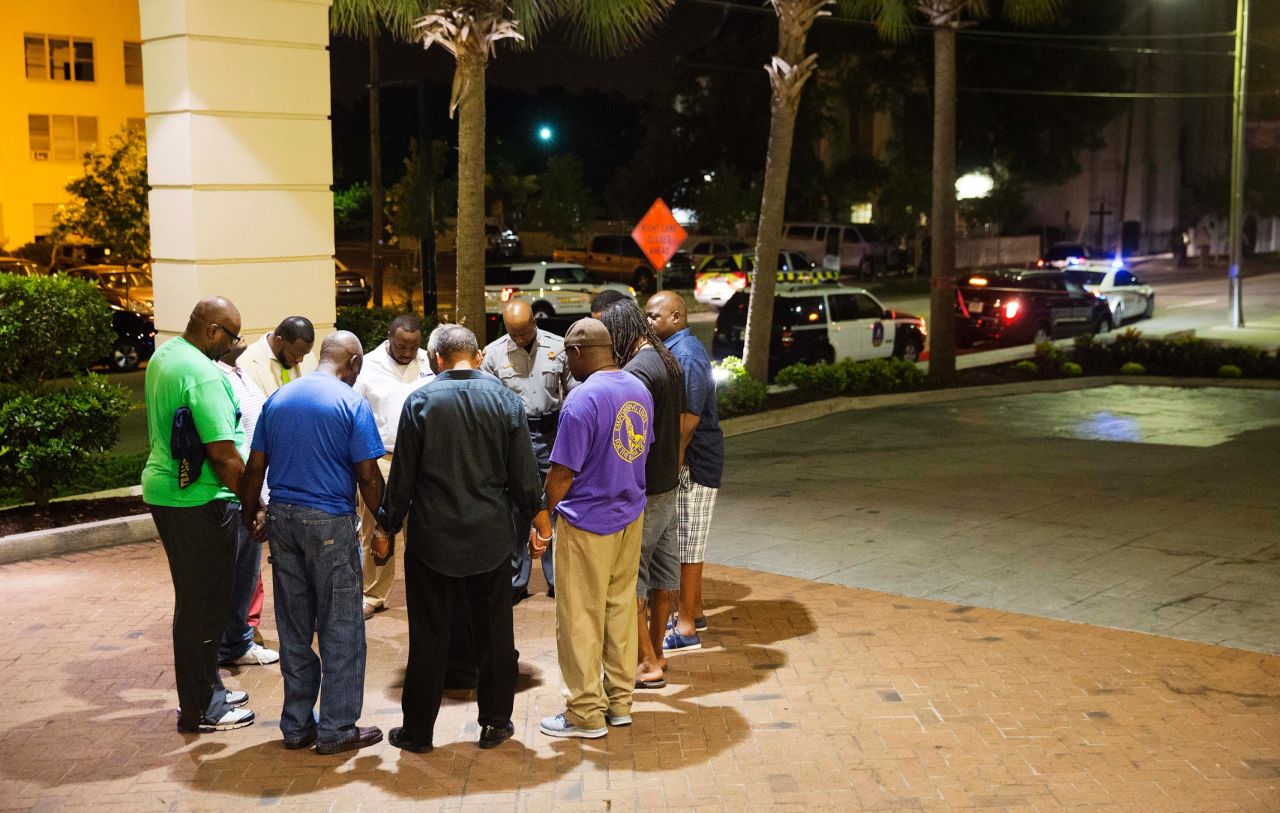 People pray in a hotel parking lot across the street from the scene of the shooting on June 17. Every Wednesday evening, the church holds a Bible study in its basement.