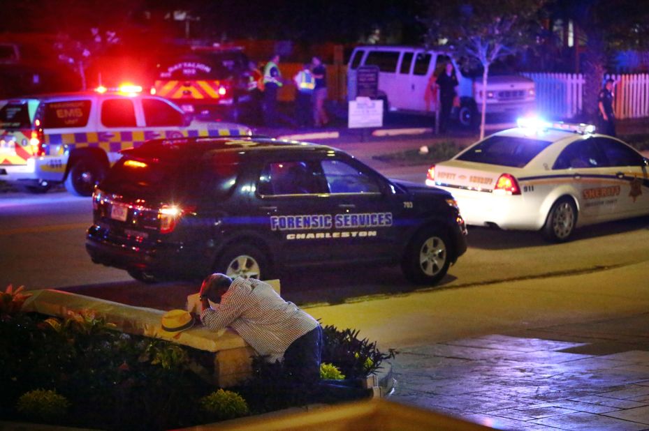 A man kneels across the street from where police gathered outside the church on June 17.