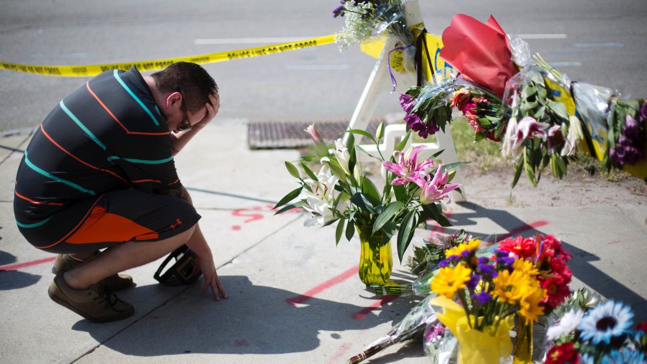 Charleston resident Noah Nicolaisen kneels at a makeshift memorial down the street from the church on June 18.