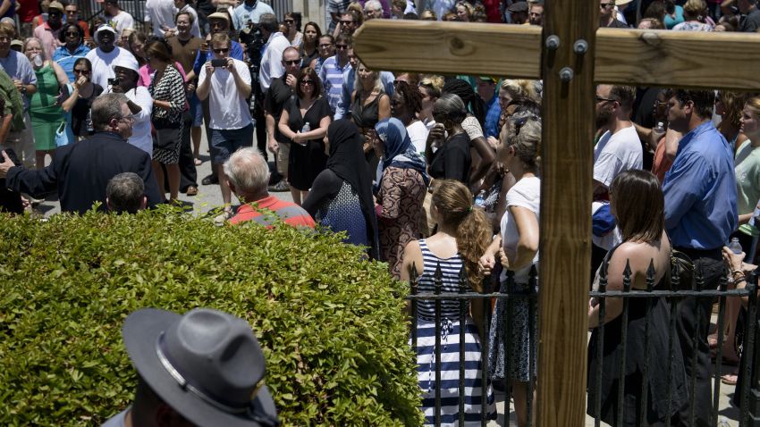 A South Carolina State Trooper walks past as people gather for a vigil while services are held at Morris Brown AME Church June 18, 2015 in Charleston, South Carolina. US police on Thursday arrested a 21-year-old white gunman suspected of killing nine people at a prayer meeting in one of the nation's oldest black churches in Charleston, an attack being probed as a hate crime. The shooting at the Emanuel African Methodist Episcopal Church in the southeastern US city was one of the worst attacks on a place of worship in the country in recent years, and comes at a time of lingering racial tensions