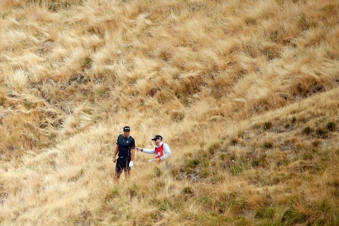 Dustin Johnson looks for his ball after a stray tee shot at the 10th hole but would recover to lead during early morning play.