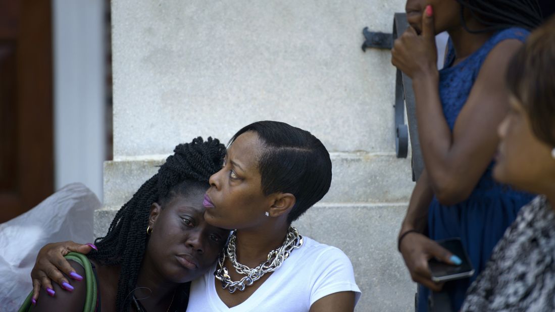 People sit on the steps of Morris Brown AME Church in Charleston while services are held June 18. 