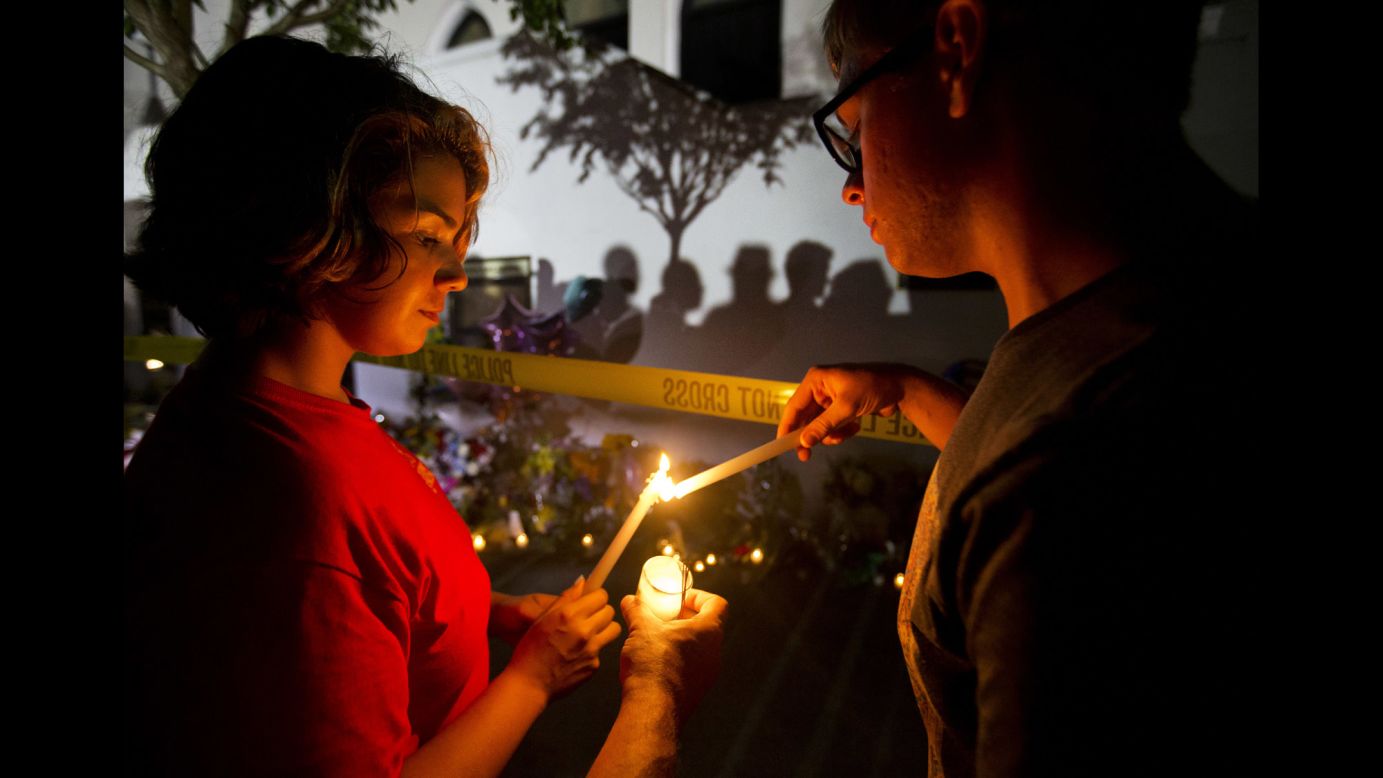 Olina Ortega, left, and Austin Gibbs light candles at a sidewalk memorial in front of Emanuel AME Church on June 18.